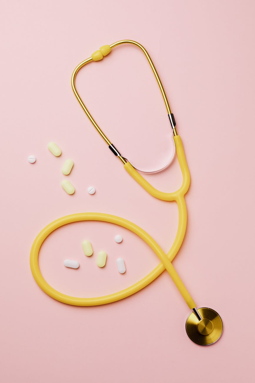 yellow stethoscope and medicines on pink background